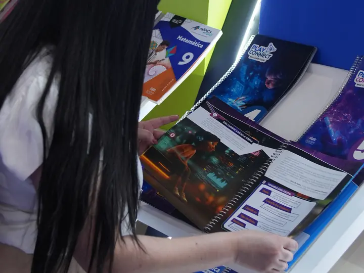 Visitante folheando um livro da Coleção Play Connect