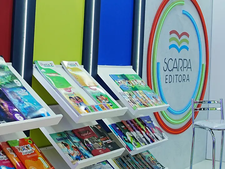 Painel da Bett Brasil e o logo da Scarpa Editora no estande